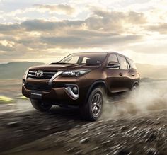 a brown toyota suv driving down a dirt road