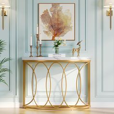 a gold console table with a marble top and two candles in front of it, against a pale blue wall