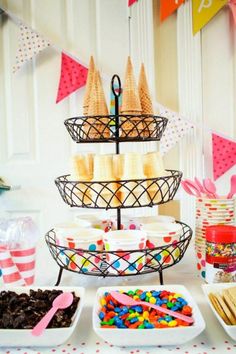 a table topped with lots of desserts next to bunting and paper streamers