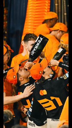 the football players are holding up their trophy in front of an orange wall and crowd