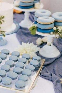 blue macaroons are arranged on a table next to white flowers and desserts