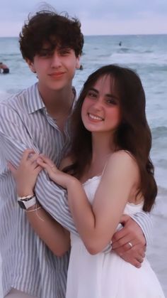 a young man and woman hugging on the beach