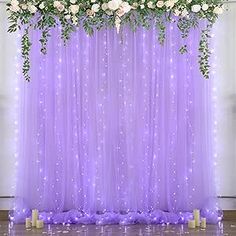 a purple backdrop with white flowers and greenery on it for a wedding or event