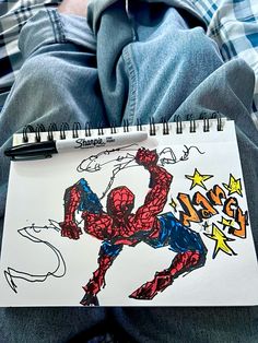 a drawing of a spider man on a piece of paper next to a person's legs