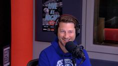 a man sitting in front of a microphone with headphones on and wearing a blue hoodie