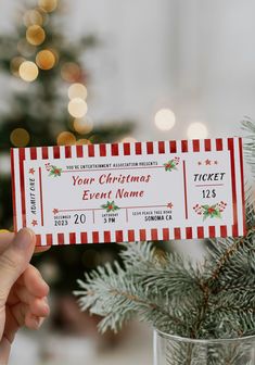 a person holding up a ticket for a christmas event in front of a decorated tree