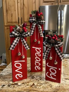 two red wooden signs with christmas decorations on them sitting on top of a kitchen counter