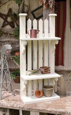 a white shelf with pots and mugs on it in front of a fenced area