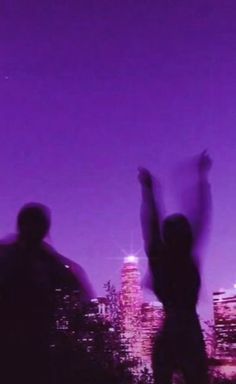 two people standing in front of a city skyline with their arms up and hands raised