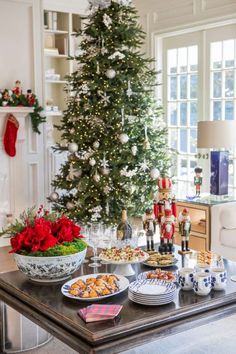 a christmas tree is in the background with plates and bowls on a table next to it