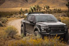 a black truck driving down a dirt road