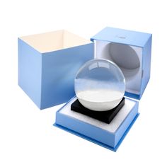 a snow globe in a blue gift box with its lid open and the base is empty