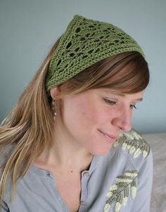 a woman wearing a knitted headband and looking down at her cell phone while sitting on a bed