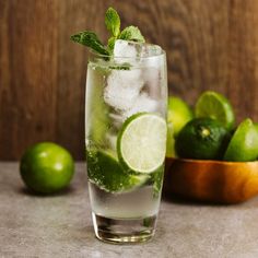 a glass filled with ice and limes on top of a table