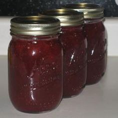 four jars filled with jam sitting on top of a counter