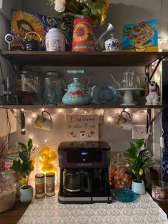 a coffee maker on top of a kitchen counter with lights strung from above and below it