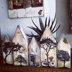 a group of wooden houses sitting on top of a shelf next to a plant and clock