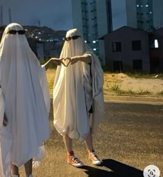 two people dressed in white walking down the street