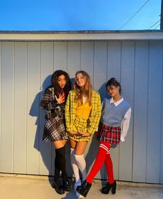 three young women standing next to each other in front of a white wall wearing short skirts and knee high socks