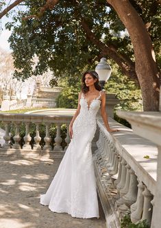 a woman in a white wedding dress standing on a balcony next to a lamp post