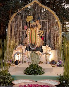 an elaborately decorated stage set up with flowers and candles in front of the statue