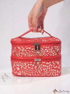 a person is holding onto a red and gold patterned box with zippers on it