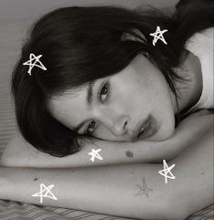 a woman laying on top of a bed covered in white stars and crosses tattoo stickers