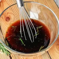 a glass bowl filled with sauce and whisk on top of a wooden table