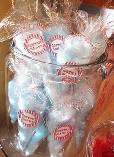 a glass jar filled with candy covered in plastic wrappers next to a bowl of strawberries