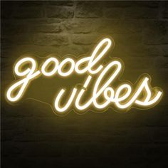 a neon sign that says good vibes in white letters on a brick wall background