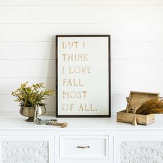 a white dresser topped with drawers next to a framed sign that says, but i think i love fall most of all