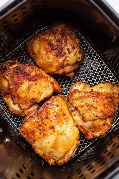 four pieces of chicken cooking on a grill