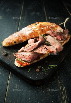 roast beef sandwich with tomato sauce and herbs on a cutting board - stock photo - images