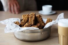 a bowl full of cookies next to a cup of coffee and a person in the background