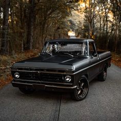 an old black pickup truck parked on the side of the road