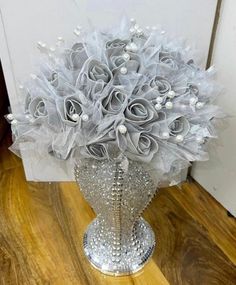 a silver vase filled with lots of white flowers on top of a wooden floor next to a door