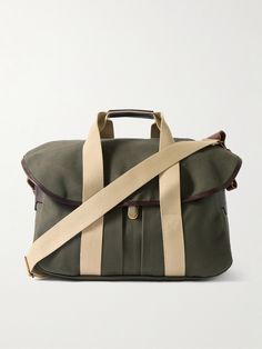 an olive green duffel bag with tan straps on the front and bottom, sitting against a white background