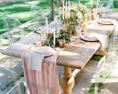 an outdoor table set up with clear chairs and flowers on the table for a formal dinner