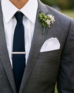 the man is wearing a suit and tie with a boutonniere on his lapel