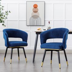 two blue chairs sitting next to each other in front of a painting on the wall