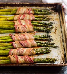 asparagus wrapped in bacon on a baking sheet