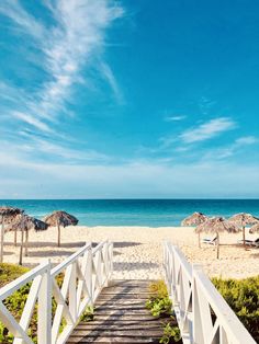 a white wooden walkway leading to the beach