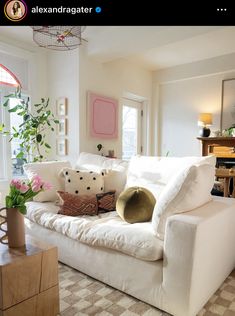 a living room with white couches and pink flowers