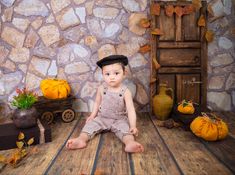 a little boy sitting on the floor in front of some pumpkins and other decorations