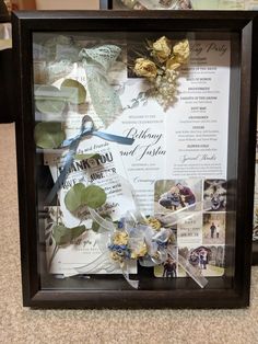 a shadow box with pictures and flowers in it on top of a carpeted floor