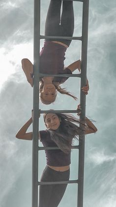 two women are standing on a ladder and one is upside down