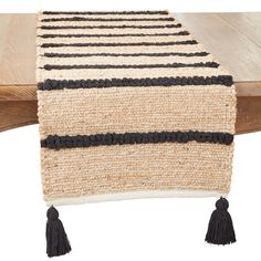 a table runner with tassels on it and a wooden bench in the background