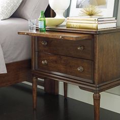 a night stand with books and drinks on it