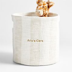 a stuffed giraffe sitting inside of a white fabric storage container with the word aroh's cars written on it