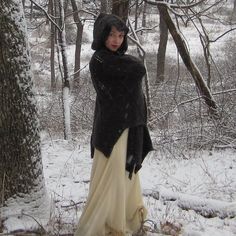 a woman is standing in the snow near a tree